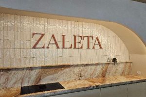 Example of indoor signage, raised brand letters on glossy tiles within an arched niche, ideal for cafés and boutiques.